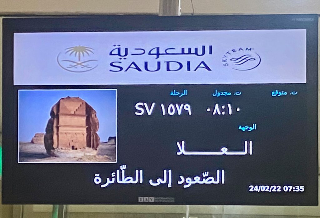 Airport flight departure sign for flight to AlUla Saudi Arabia