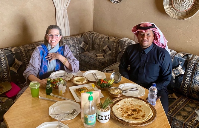 a man and woman sit at a table with dishes of food before them