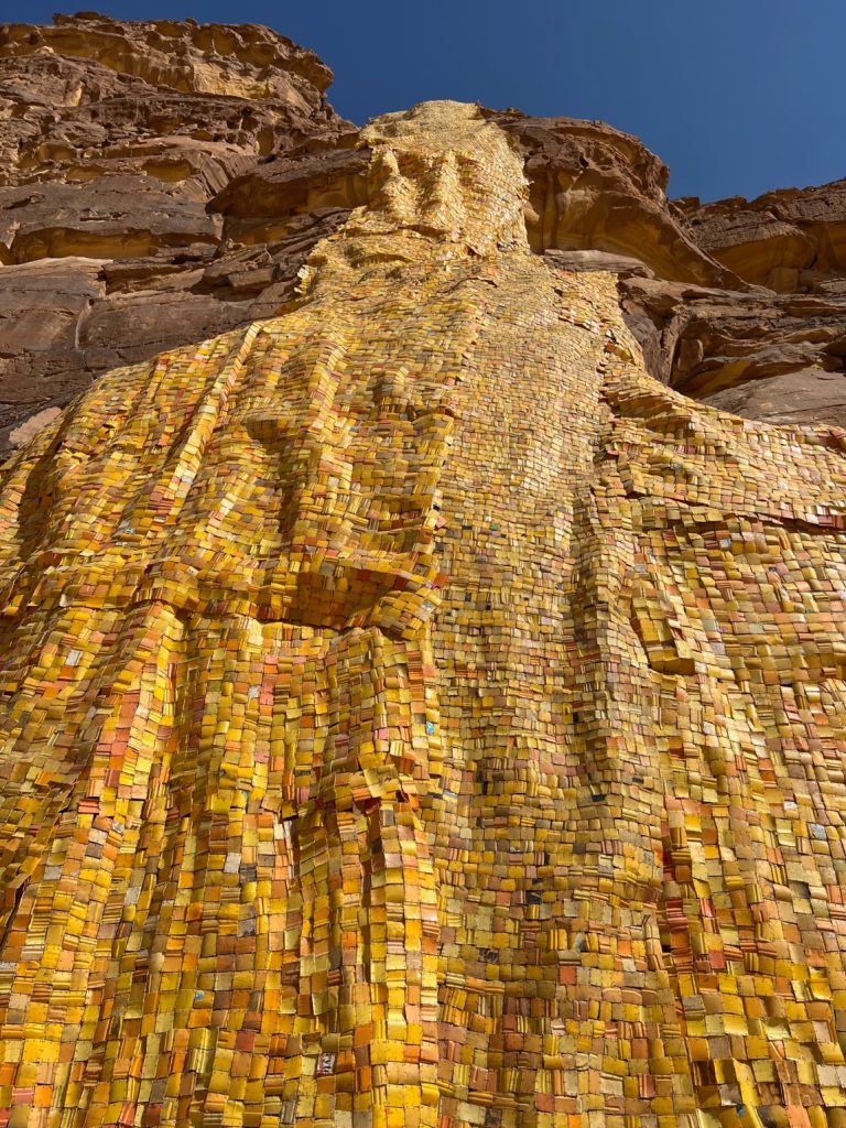 many yellow squares affixed to a cliff in the shape of a waterfall