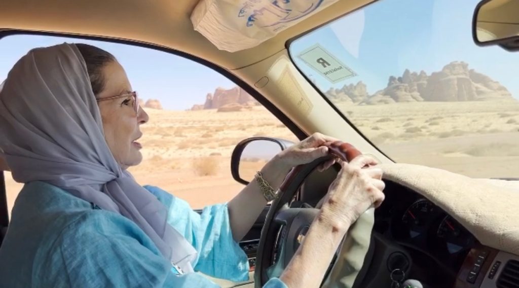 woman in a blue abaya holding the steering wheel while driving a vehicle