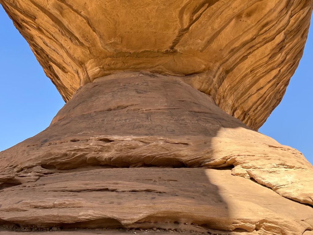 two large rocks meet beneath a blue sky