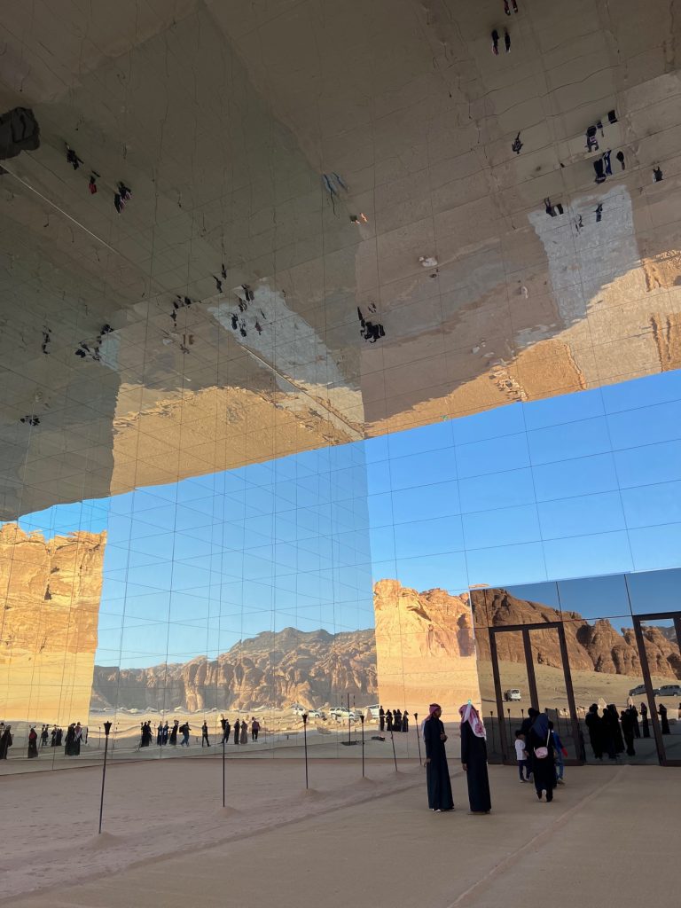 individuals stand next to a large mirrored building