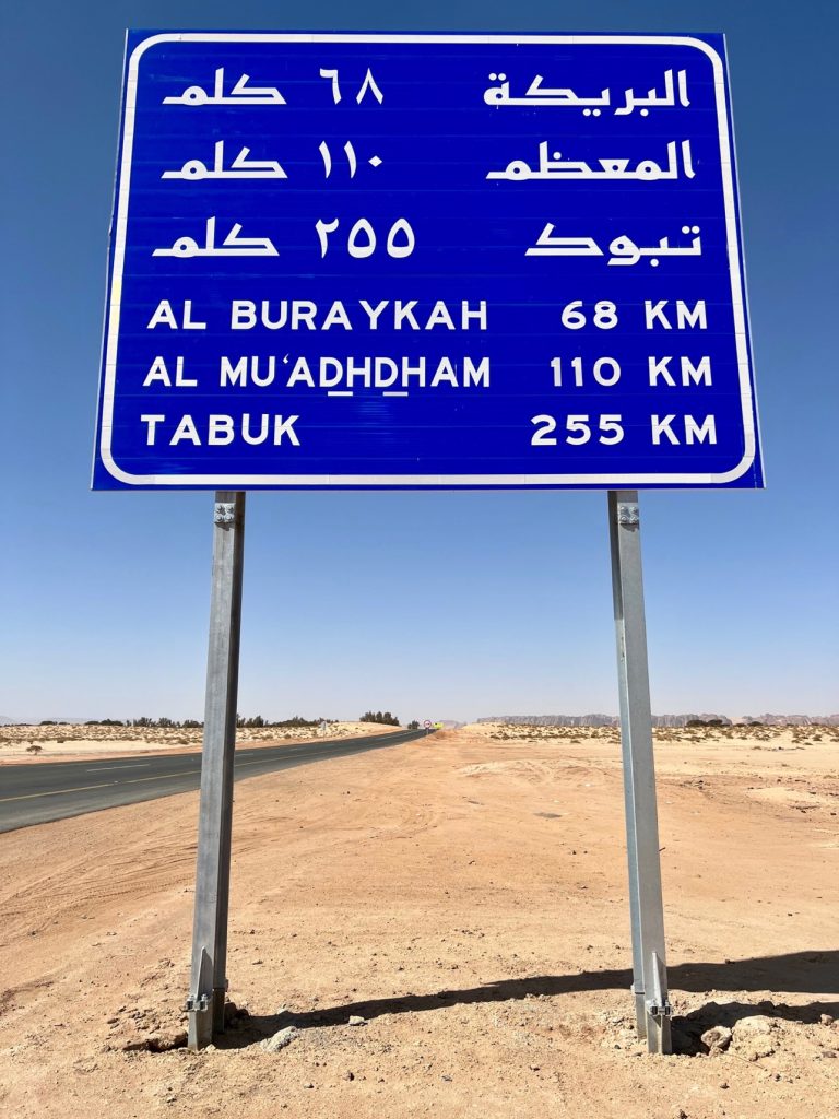 blue road sign with Arabic and English writing