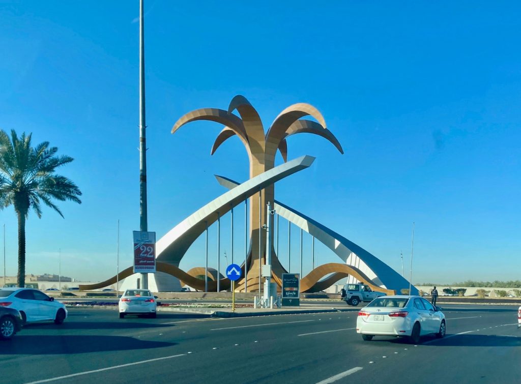road roundabout with a large metal palm tree sculpture in the middle