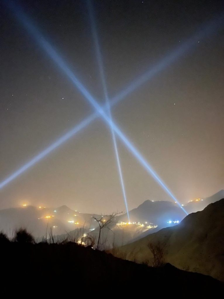 three spotlights intersect in a night sky