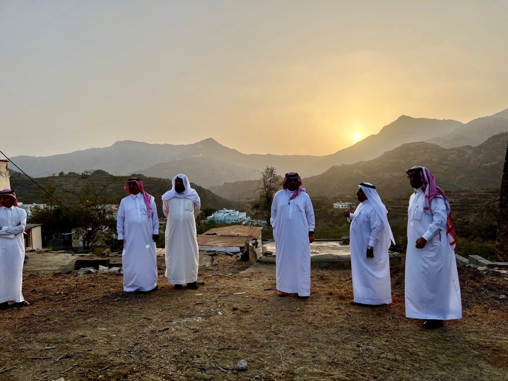 Men in white thobes standing again a mountain backdrop