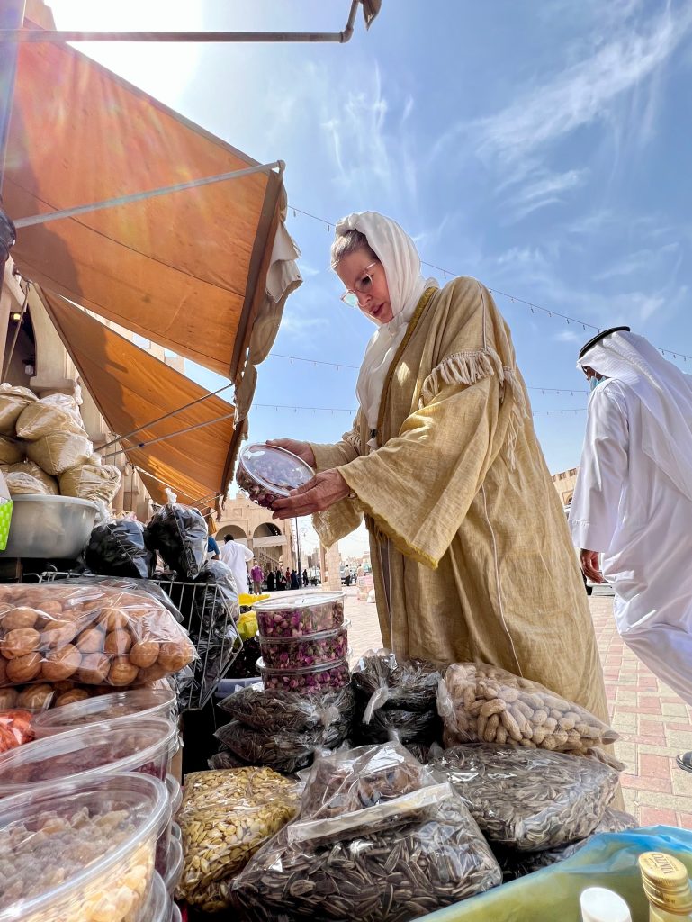 a woman in a golden abaya looking at shop goods