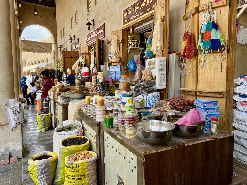 various spices and other goods on display for purchase at a shop on the outer corridor of a market