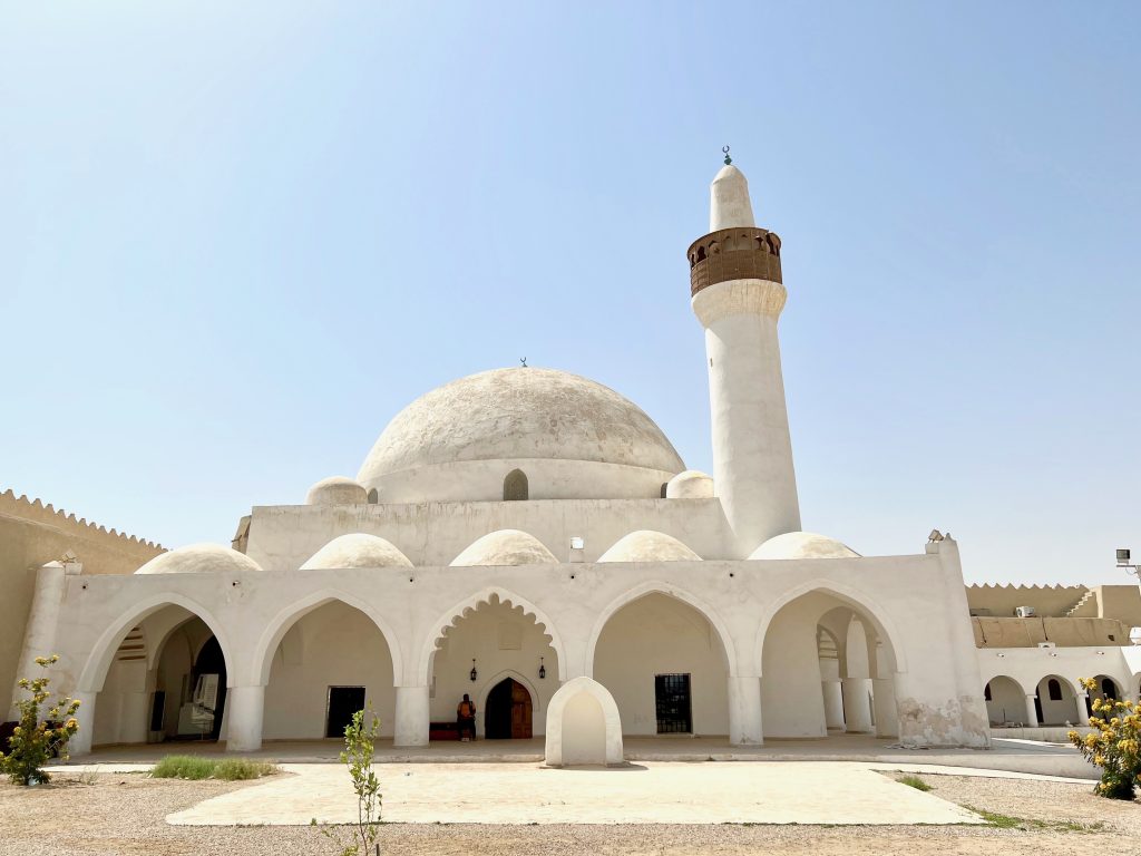 a white stone mosque with a domed roof and a minerat