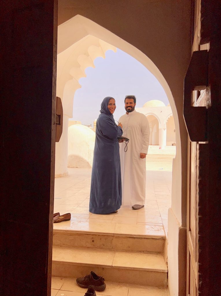 a woman in a blue abaya standing with a younger man in a white thobe