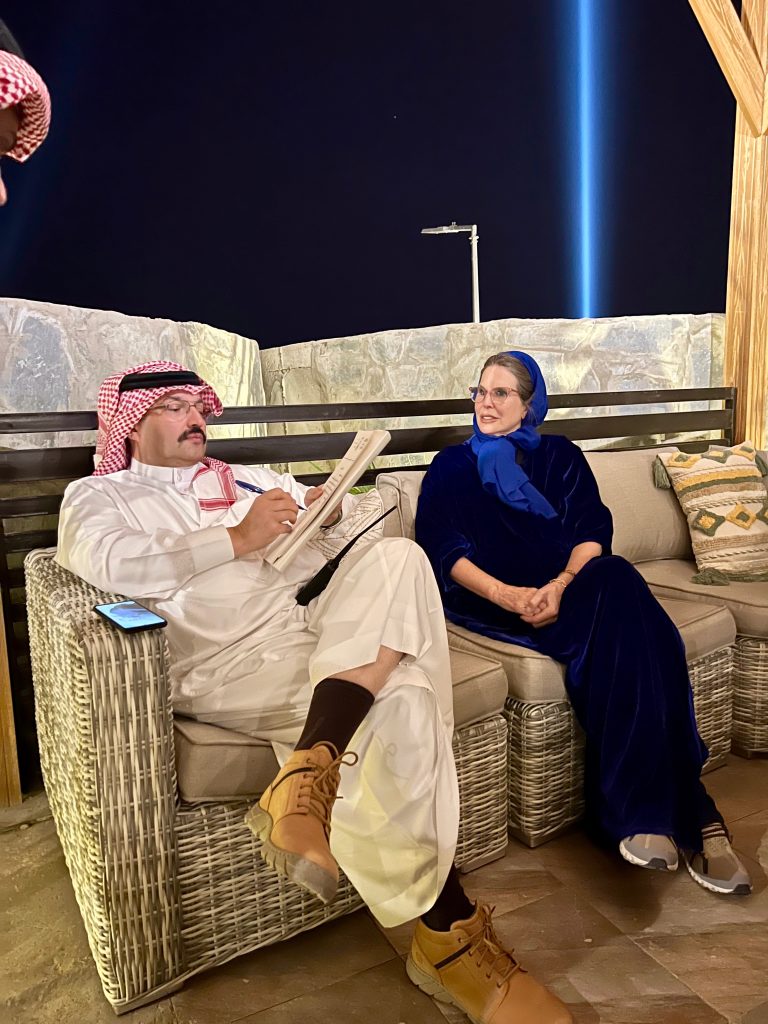 a man in a white thobe sits adjacent to a woman in a blue abaya