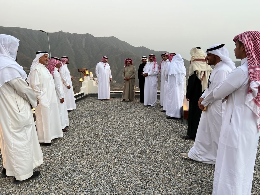 a group of men wearing thobes standing on a flat gravel rooftop