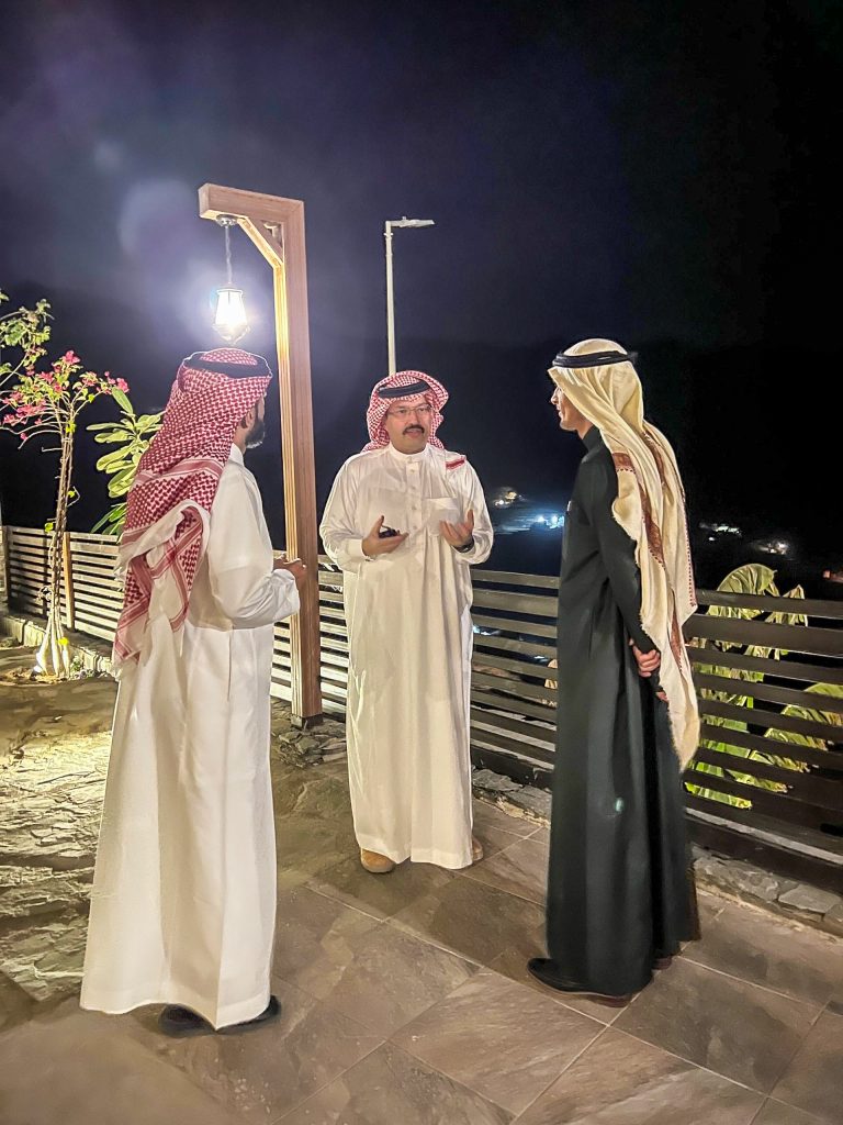 three men in thobes standing and talking