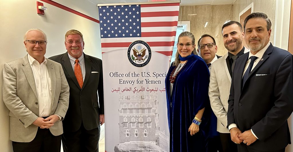 four people stand facing the camera with a popup banner saying *Office of the US Special Envoy to Yemen*