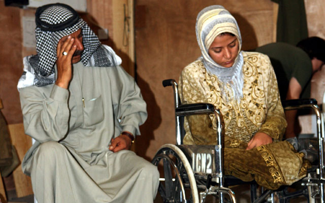 A woman from Al-Karabilah, Iraq, wounded during violence occasioned by the U.S.-led invasion and occupation of Iraq, waits for medical care.